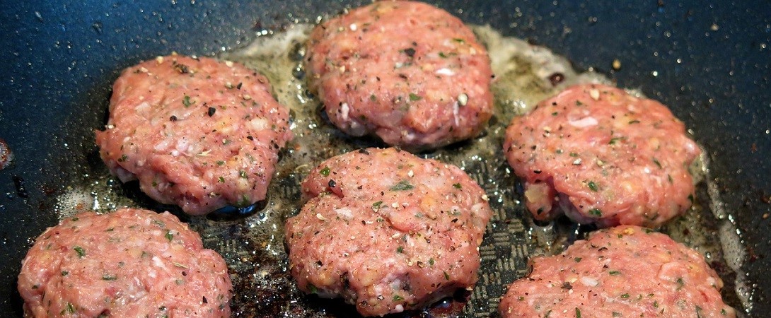 minced meat being cooked with olive oil in a frying pan