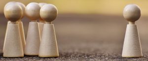 a group of wooden pieces standing together opposite a single wooden piece