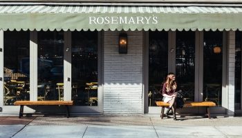 a woman sitting outside a Rosemary's restaurant