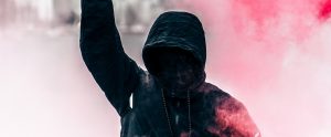 a radical in a black hoodie with red mist around him