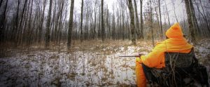 hunter in high visibility vest sitting in a chair waiting for prey
