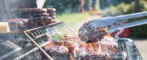 burgers being barbecued with tongs