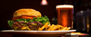 a burger and fries near a pint of alcohol