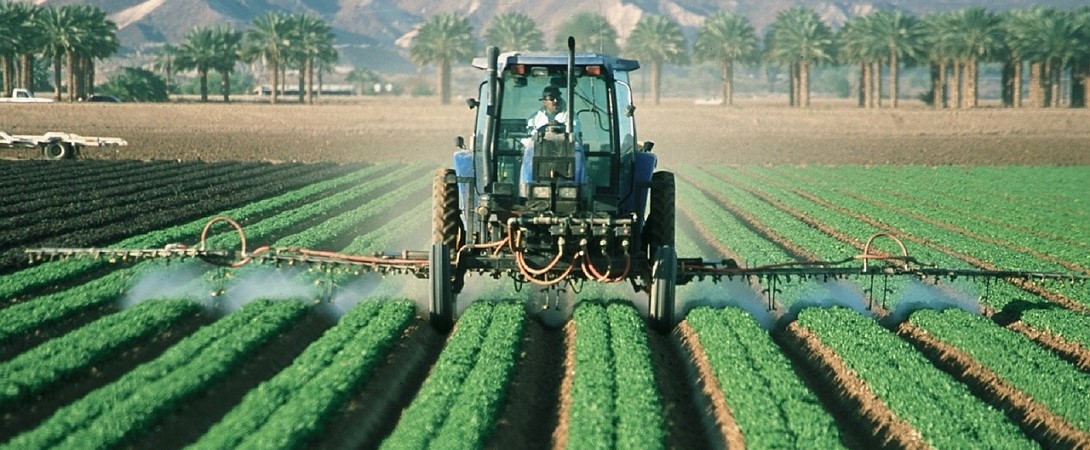 a tractor depositing fertilizer onto crops