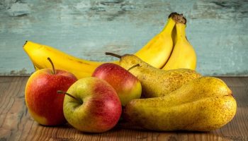 group of apples, pear and bananas on a wooden surface
