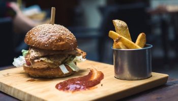 burger next to ketchup and fries on a wooden board