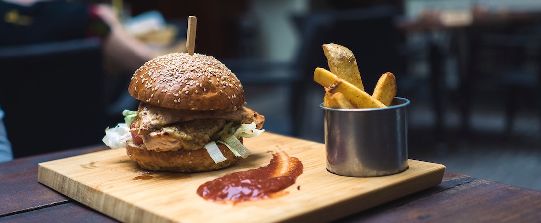 burger next to ketchup and fries on a wooden board
