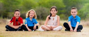 four children sitting in a field