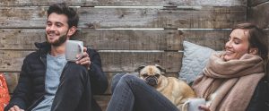 a man and a woman sitting together with a pug between them
