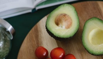two avocados on a wooden cutting board
