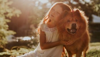 a young girl hugging her pet dog