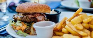 a meat, cheese and bacon burger with fries, and mayonnaise in a bowl on a plate