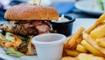 a meat, cheese and bacon burger with fries, and mayonnaise in a bowl on a plate