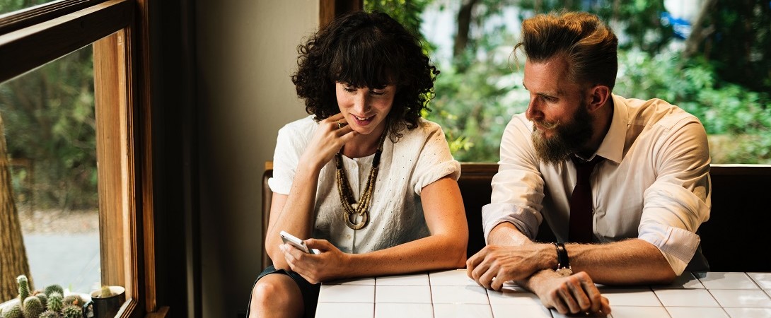 a bearded man and a woman looking at a phone