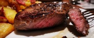 medium rare steak and potatoes being eaten with a fork