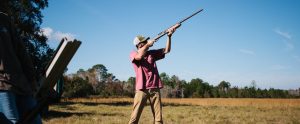 man in nature shooting with a shotgun