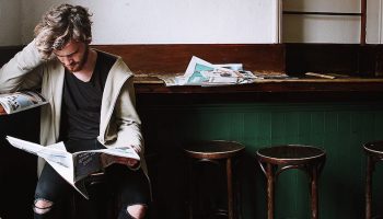 man puzzled whilst reading a newspaper
