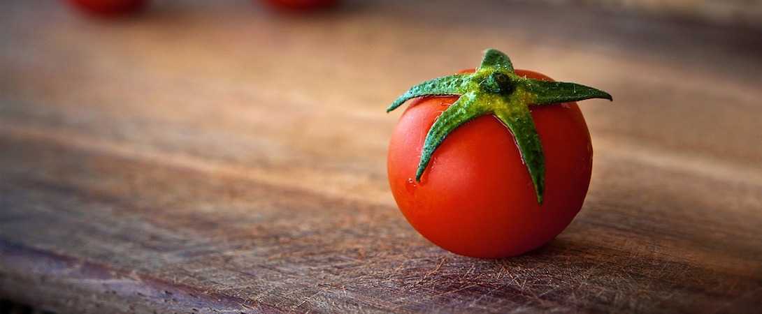 fresh wet tomato on wooden cutting board