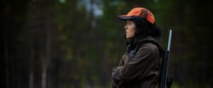 a female hunter with a hunting rifle over her shoulder