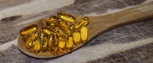 yellow vitamin pills on a wooden spoon