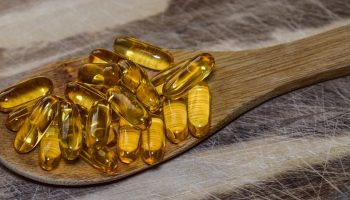 yellow vitamin pills on a wooden spoon