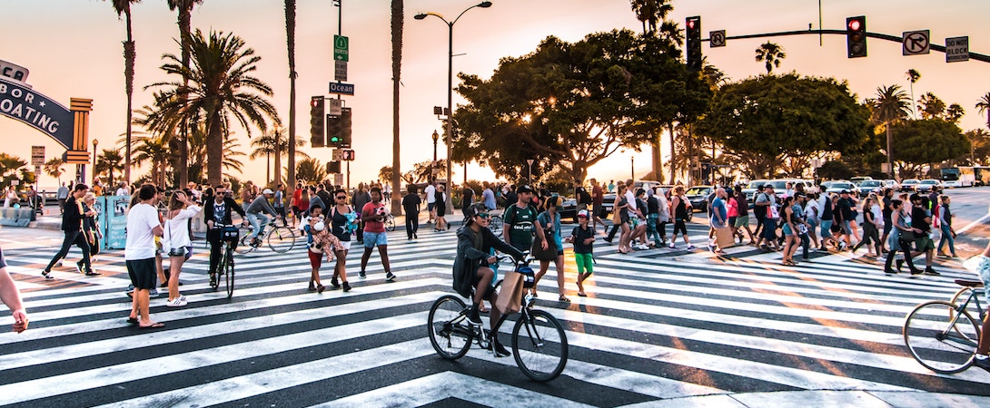 crowds of people crossing a road by foot and bike