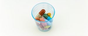different colored pills in a see-through beaker