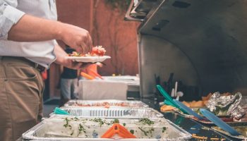 a fat man taking food from a buffet