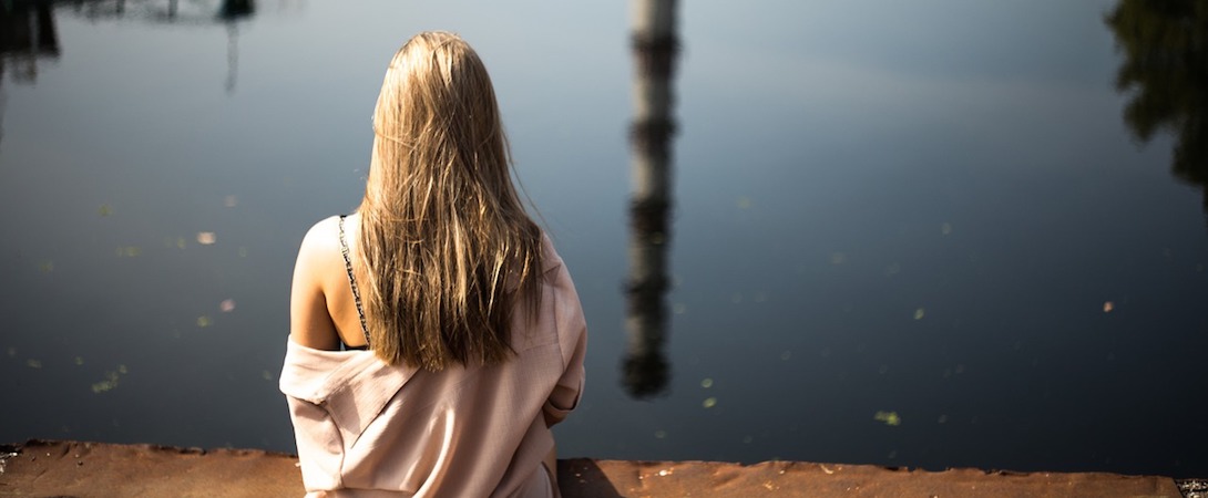 woman sitting and staring at water