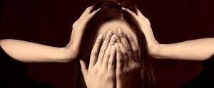 woman with hands covering her face and ears