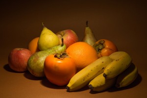 various fruits grouped together and softly lit on a brown surface