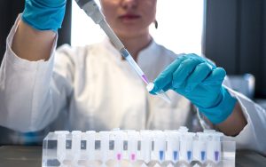 Scientist pipettes colored chemicals into tubes.