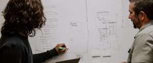 Two people writing on a whiteboard