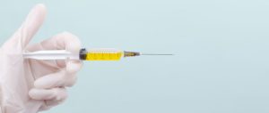 gloved hand holding a syringe