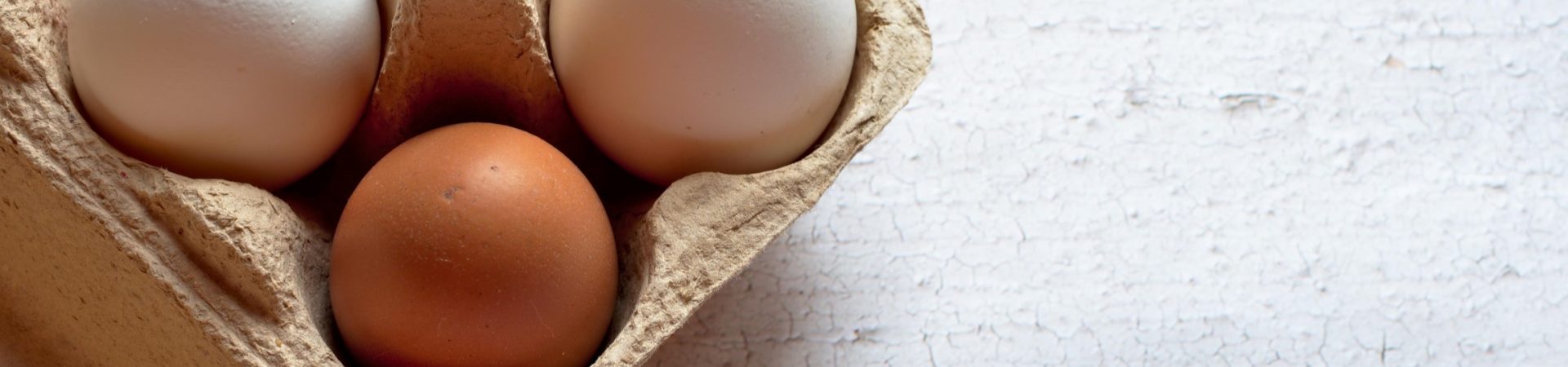 carton of brown and white eggs on wooden table background