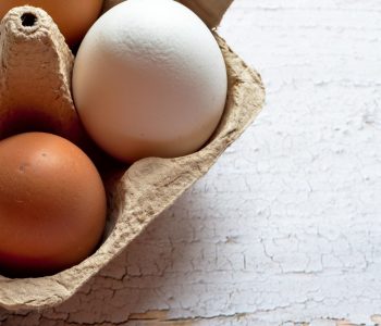 carton of brown and white eggs on wooden table background