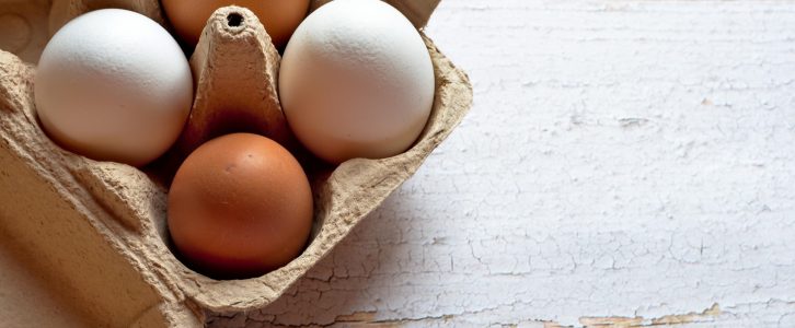 carton of brown and white eggs on wooden table background