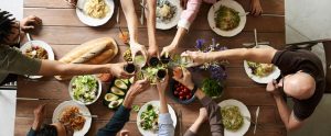 group of people having meal together clinking glasses over table