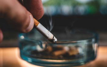 hand holding a cigarette near an ashtray