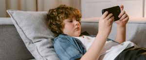 child lying on couch watching smartphone