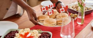person putting plate of burgers with Canadian flags on table
