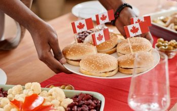 person putting plate of burgers with Canadian flags on table