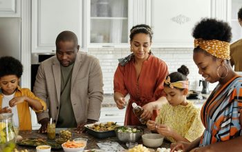 family standing around kitchen island eating together