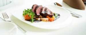 steak with gravy and vegetables on white plate