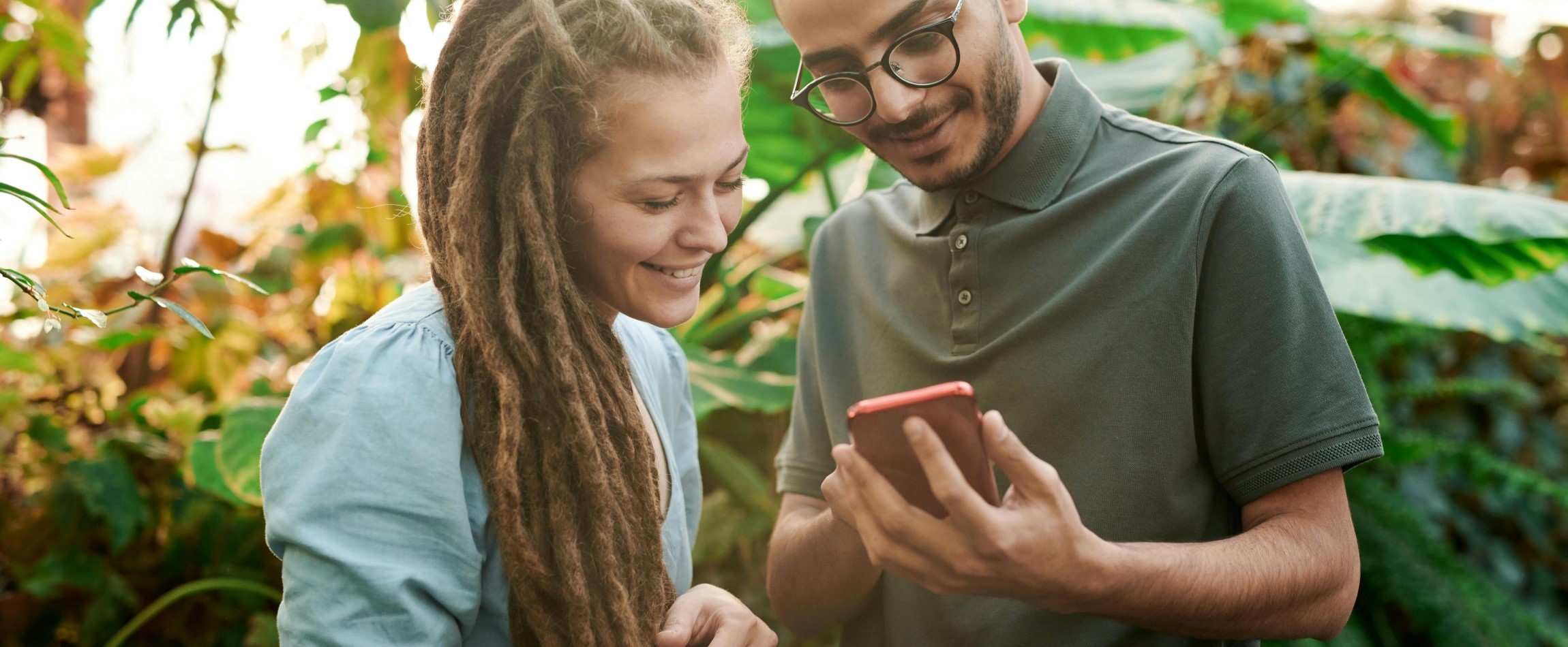 two people outdoors looking at smartphone together