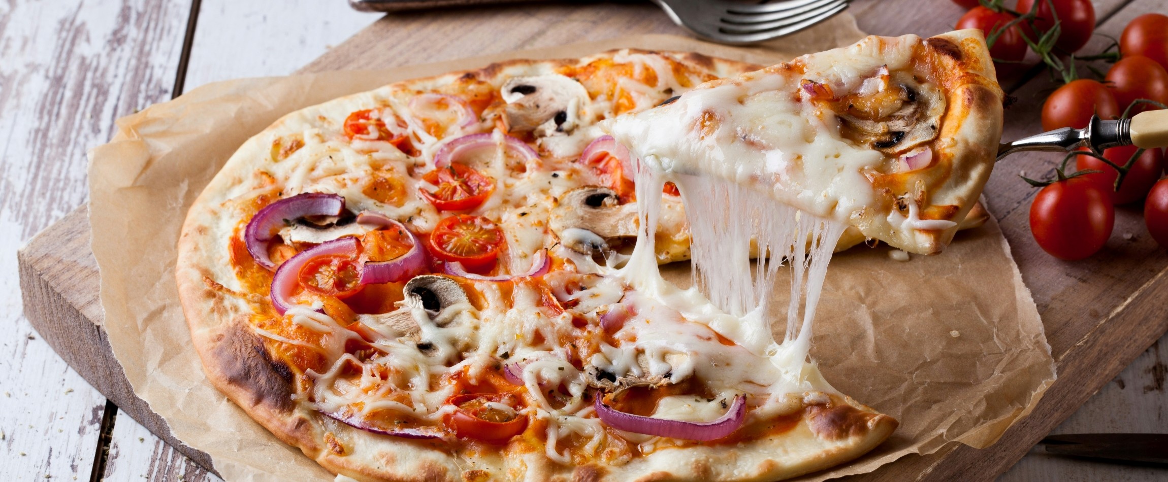 cheesy slice of pizza being lifted off wooden board