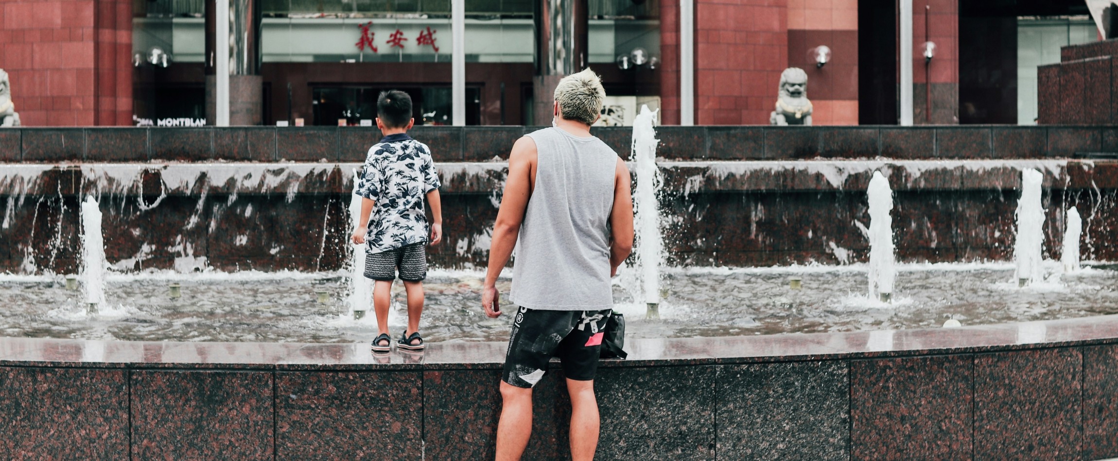 man and child standing next to outdoor fountain Ngee Ann City Singapore