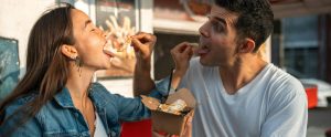 two people feeding each other fries outdoors