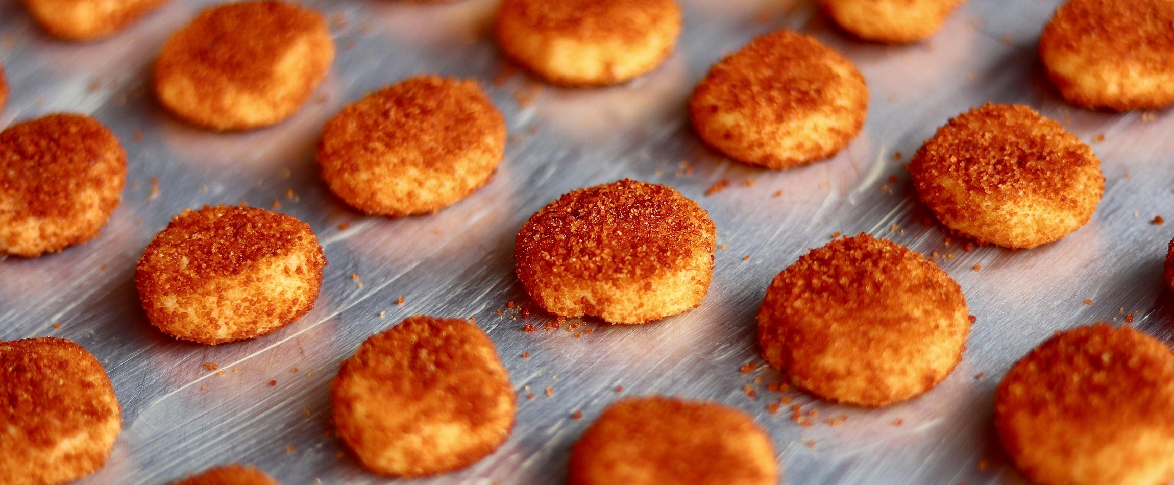 close-up of rows of chicken nuggets on stainless steel tray
