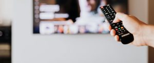 hand holding remote control pointed at television